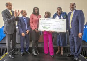 Empowered women receiving a large donation check at a formal event for community support and develop.