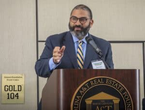 An image of a man speaking at a conference podium during a professional event.