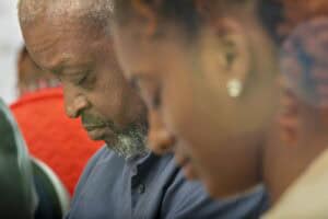 Senior man and young woman with closed eyes, attending a community event or gathering.