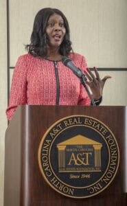 A woman speaking at a podium with the North Carolina A&T State University logo, delivering a speech.