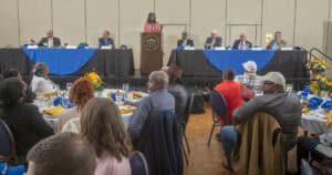 High-level conference with diverse speakers and audience at a formal event in a large hall.