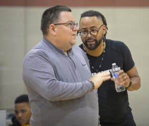 Engaged discussion between two men at an indoor event, one holding a water bottle, emphasizing commu.