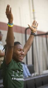 Empowered young girl raising hands at a community event for youth leadership.