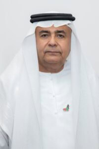 A man wearing traditional Middle Eastern attire, including a white kandura and black agal, posing co.