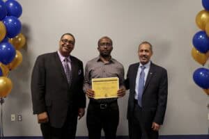 Celebration of achievement with three men holding a certificate at an event.