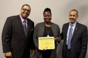 Diverse professionals at award ceremony with certificate of recognition.