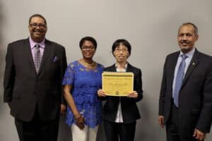 Diverse professionals at CAES News event with certificate presentation.