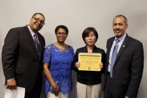 Celebration of achievement with diverse professionals holding a certificate at CAES News event.