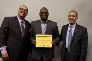 Three professional men in suits celebrating an award or certificate presentation.