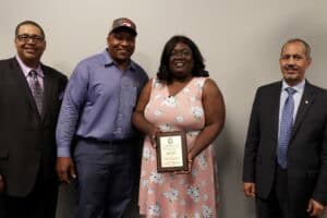 Celebration of achievement with diverse professionals holding award plaque at CAES News event.