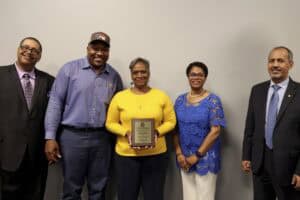 Celebration of achievement with diverse group of professionals holding award plaque at CAES News eve.