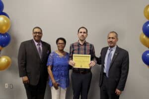 Celebration of achievement with four diverse professionals, one holding a certificate, in a formal s.