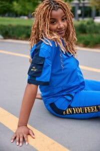 Bright young woman in blue uniform sitting on the street during daytime, promoting community safety.