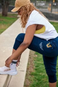 Woman tying her shoelaces outdoors in casual sportswear for fitness or running.