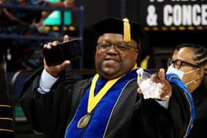 Graduation graduate celebrating with cap and gown at ceremony.
