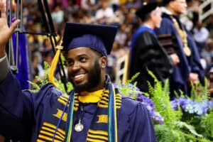 Graduation student in cap and gown celebrating at commencement ceremony with friends and family.
