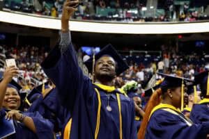 Graduates taking a selfie at a university graduation ceremony in caps and gowns.