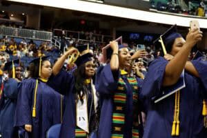 Graduates in caps and gowns celebrating at a graduation ceremony.