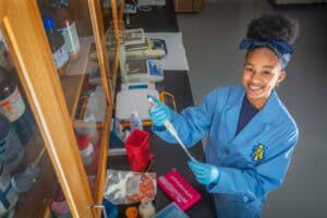 Bright female scientist working in a laboratory with lab equipment and chemicals.