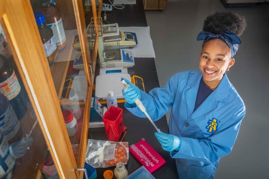 Bright female scientist working in a laboratory with lab equipment and chemicals.