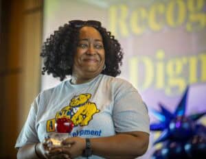 Woman holding an award at CAES News event, smiling and celebrating achievement.
