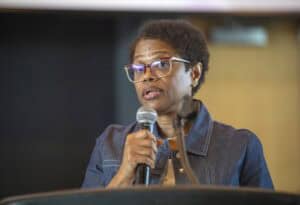 A woman speaking into a microphone at a conference or event.