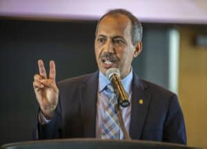 Professional male speaker at conference delivering speech with hand gesture.