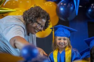 Graduation celebration with a smiling young girl in blue cap and gown at ceremony.