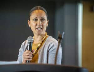 Empowered woman speaking into microphone at conference for leadership and professional development.