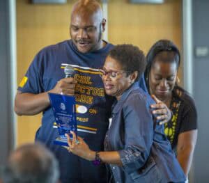 Empowering community recognition at CAES News event with diverse group celebrating achievement.