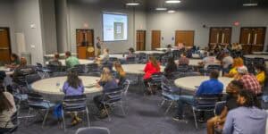 Conference room with attendees listening to a presentation at CAES News event.