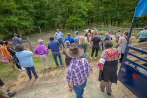 Community outdoor gathering with speaker in a park setting, diverse group listening attentively.