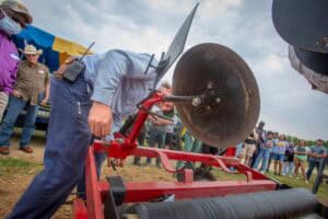 High-voltage power line cutting demonstration at outdoor event with crowd and officials present.
