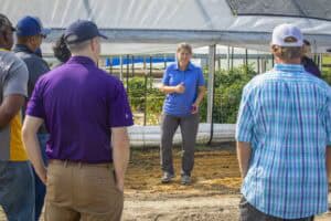 Plant science instructor explaining greenhouse techniques to students in an agricultural training se.