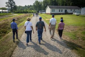 Community members walking on a gravel path in a rural area with mobile homes.