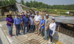 Agricultural team inspecting farm construction site with damaged barn in rural setting.