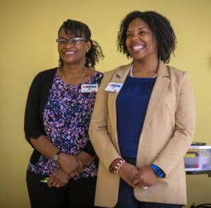 Empowered women smiling at a professional event, showcasing diversity and confidence in leadership.