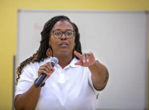 Woman speaking into microphone during presentation at CAES News event.