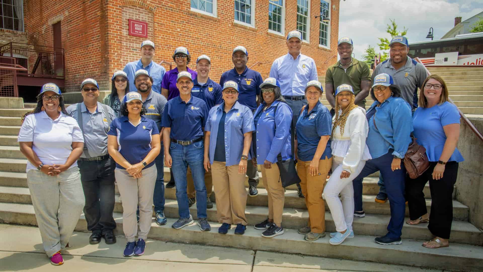 Volunteers and staff of CAES News team outdoors in front of a brick building.