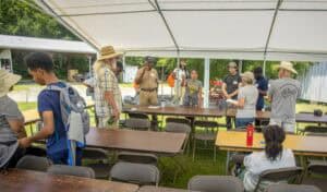 Community outdoor event with diverse group under tent setup.