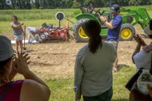 Farmers and agricultural experts discussing tractor equipment in a rural field.