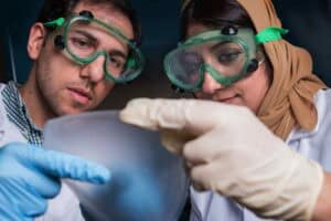 A scientist and a researcher examining a sample with laboratory tools.