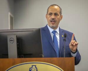 Male speaker in a blue suit giving a presentation at a conference.