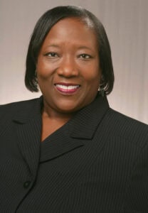 Empowered professional woman smiling in formal business attire for CAES News feature.