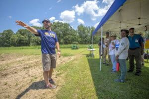 Community event with speaker and attendees outdoors on a sunny day at CAES News.