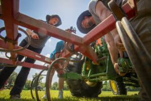 Plantation workers inspecting agricultural machinery in a field.