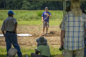 People working outdoors on a farm or garden with tools and equipment.