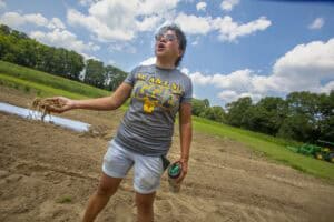 CAES News woman speaking outdoors on farm field with tractor in background.