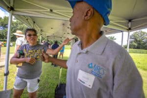 Community outreach event with people engaging outdoors under a tent, promoting health and wellness i.