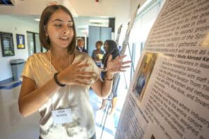 A woman presenting a research poster at a conference or academic event.